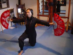 Anna Yen kneeling with two fans.